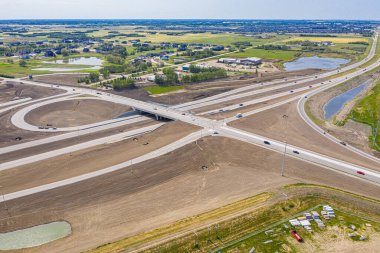 Büyük bir üst geçidi ve kırmızı bir arabası olan bir otoyol. Otoyol yapım aşamasında ve çok trafik var.