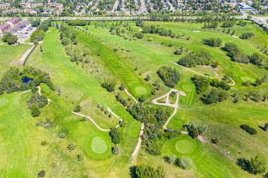Yeşil çimenli tepeli ve ağaçlı golf sahası. Golf sahası iyi korunuyor ve huzurlu bir atmosferi var.