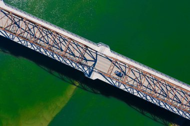 Üzerinde araba olan bir köprü. Köprü yeşil ve su da yeşil.