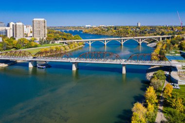 Köprü, arka planda bir şehir bulunan bir nehri kapsar. Köprü eski ve kırsal bir görünüme sahip.