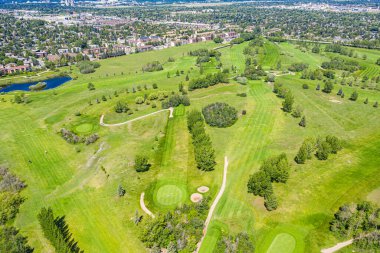 Yeşil çimenli çayırları ve ağaçları olan golf sahası. Golf sahası yerleşim bölgesinde.