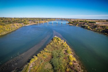 Ortasında köprü olan bir nehir. Su sakin ve gökyüzü berrak. Köprü uzun ve nehir boyunca uzanıyor.