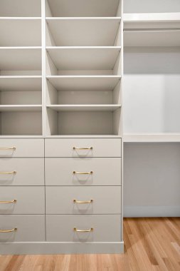 Masası ve çekmecesi olan beyaz bir dolap. Dolap çok temiz ve düzenli. Masa boş ve çekmeceler açık.