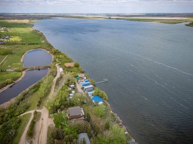 Kıyısında küçük bir kasaba olan göl. Su sakin ve gökyüzü bulutlu.