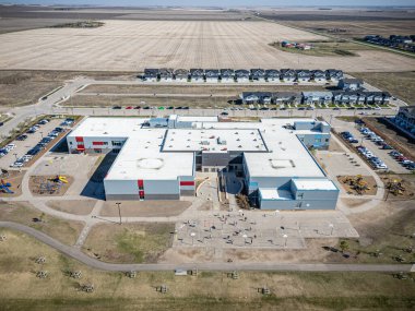 Bir sürü otoparkı ve çocuk parkı olan büyük bir okul binası. Okul bir sürü ot ve ağaçla çevrili.