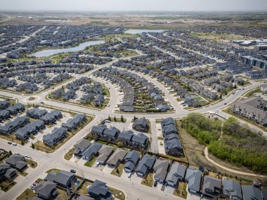 Arka planda evleri ve gölü olan bir banliyö mahallesi. Evlerin çoğu beyaz ve caddeye park edilmiş bir sürü araba var.