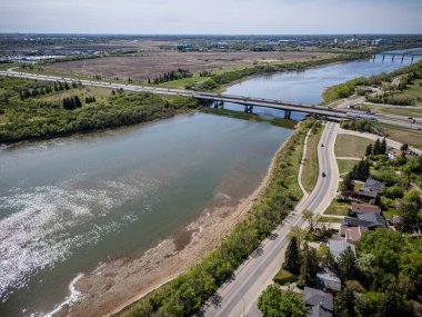 Üzerinde köprü olan bir nehir manzarası. Köprü yola yakın ve arka planda evler var.