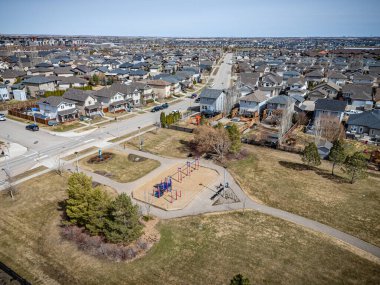 Park yeri ve arka planda birkaç ev var. Park boş ve gökyüzü temiz.