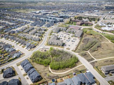 Ortasında park olan bir yerleşim yeri. Park evlerle çevrili ve bir oyun alanı var. Bölgede park etmiş bir sürü araba var ve cadde ağaçlarla dolu.