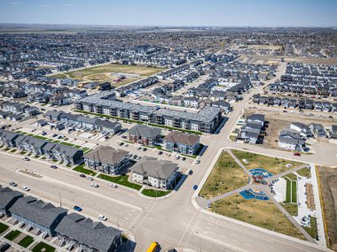 Ortasında park olan bir şehir caddesi. Park evlerle çevrili ve bir oyun alanı var.