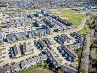 Bir sürü evi ve birkaç arabası olan bir yerleşim yeri manzarası. Evlerin çoğu beyaz ve arabalar caddeye park edilmiş.