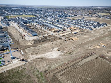 Arka planda inşaat alanı olan bir şehir caddesi. İnşaat alanı caddenin ortasında ve evlerle çevrili.