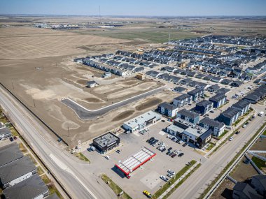 Ortasında benzin istasyonu olan büyük boş bir arazi. Arazi çitlerle çevrili ve arka planda birçok ev var.