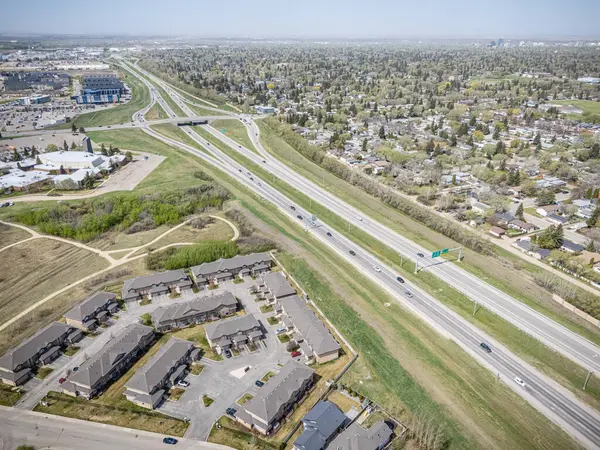 Arka planda otoyol olan bir şehir caddesi. Otoyol arabalar ve kamyonlarla dolu. Şehir konut ve ticari alanların bir karışımıdır.