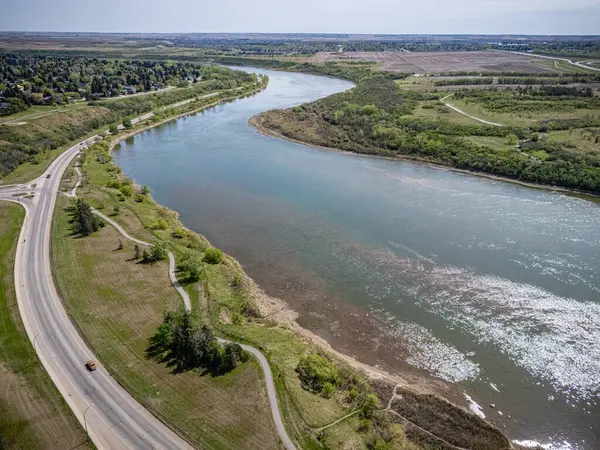 Yanı başında akan bir yol olan nehir. Yol arabalar ve kamyonlarla dolu. Gökyüzü açık ve su sakin.
