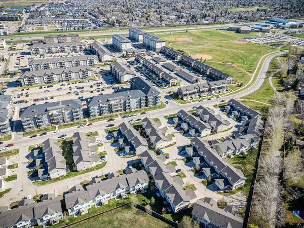 Bir sürü evi ve birkaç arabası olan bir yerleşim yeri manzarası. Evlerin çoğu beyaz ve arabalar caddeye park edilmiş.