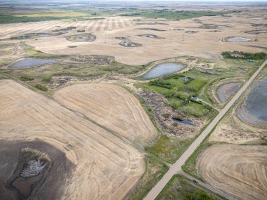 İçinden yol geçen büyük bir tarla. Yol göletlerle kaplı ve toprak çoğunlukla kuru.