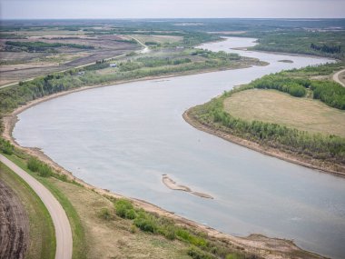 Sağ yakasında yeşil orman olan bir nehir. Su sakin ve berrak. Gökyüzü mavi ve güneş parlıyor.