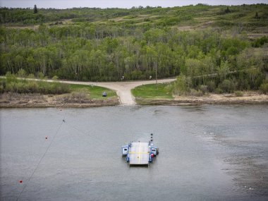 Limanın yakınındaki bir gölde küçük bir feribot yüzüyor. Su sakin ve gökyüzü bulutlu.