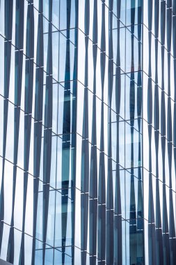 Bir sürü penceresi olan büyük bir bina. Pencereler hareket ve derinlik hissi yaratacak şekilde düzenlenmiş. Bina modern ve şık görünüyor.