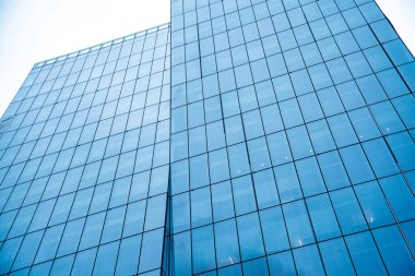 Mavi yüzlü, uzun bir bina. Pencereler geniş ve temiz, bu da çok fazla doğal ışığın içeri girmesine olanak sağlıyor. Bina modern bir ofis binası gibi görünüyor.