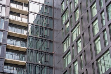 Bir sürü penceresi ve balkonu olan büyük bir bina. Bina çok yüksek ve bir sürü penceresi var, modern ve şık bir görünüme sahip. Balkon güzel bir dokunuş.