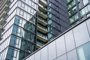 Bir sürü penceresi ve balkonu olan yüksek bir bina. Bina çok yüksek ve bir sürü cam penceresi var.