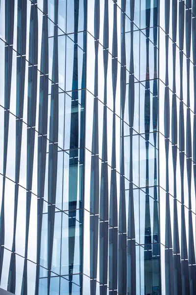 Bir sürü penceresi olan büyük bir bina. Pencereler hareket ve derinlik hissi yaratacak şekilde düzenlenmiş. Bina modern ve şık görünüyor.