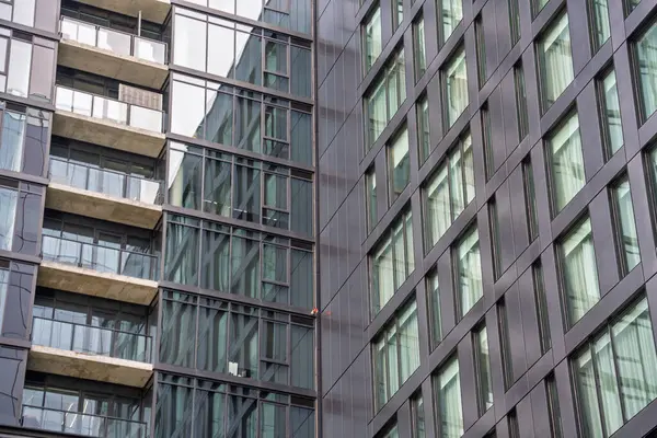 Bir sürü penceresi ve balkonu olan büyük bir bina. Bina çok yüksek ve bir sürü penceresi var, modern ve şık bir görünüme sahip. Balkon güzel bir dokunuş.