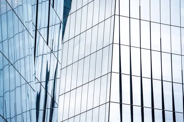Bir sürü penceresi ve gökyüzünün yansıması olan yüksek bir bina. Bina çok modern ve şık.