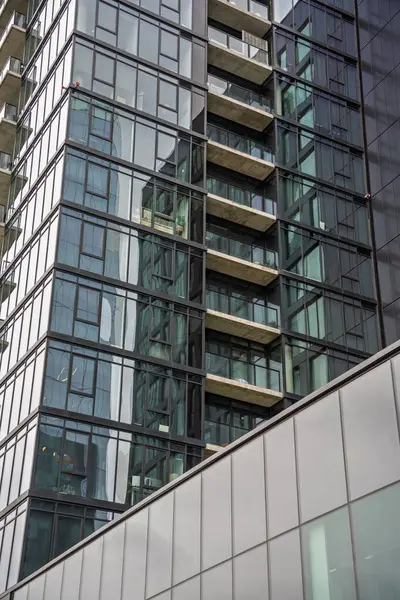 Bir sürü penceresi ve balkonu olan yüksek bir bina. Bina çok yüksek ve bir sürü cam penceresi var.