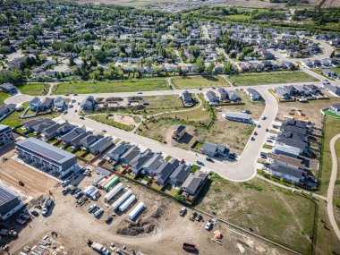 Evleri ve şantiyesi olan bir yerleşim yeri. Evler inşaatın çeşitli aşamalarında ve bölgede çok sayıda kamyon ve araba var. Sahne gelişim ve gelişmelerden biridir.