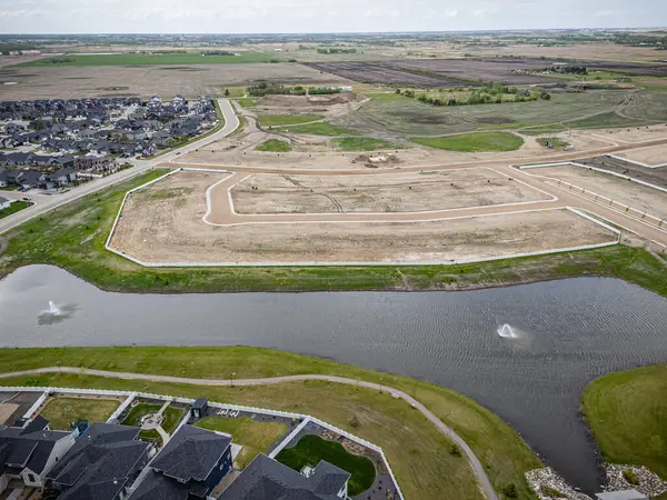 Arka planda büyük bir su kütlesi olan yerleşim yeri manzarası. Evler dağılmış durumda ve bölgede birkaç ağaç var.