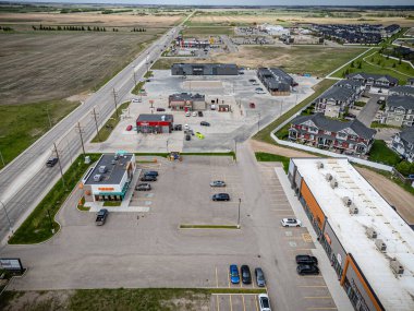 Arka planda birkaç araba ve birkaç bina olan büyük boş bir otopark. Binaların çoğu beyaz ve birkaç penceresi var.