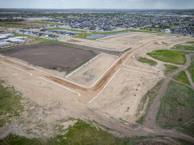 Bir sürü toprak ve çimen olan yerleşim yeri manzarası. Evler dağılmış ve bazı inşaat alanları var.