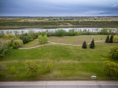 İçinden nehir akan geniş, açık bir alan. Gökyüzü bulutlu ve çimenler yeşil