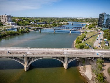 Köprü, arka planda bir şehir bulunan bir nehri kapsar. Köprü nehrin iki tarafını birbirine bağlayan büyük bir yapıdır.