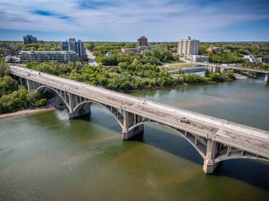 Köprü, arka planda bir şehir bulunan bir nehri kapsar. Köprü iki bölgeyi birbirine bağlayan büyük bir yapıdır.