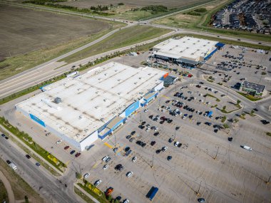 Arabalarla dolu bir otoparkı olan büyük bir alışveriş merkezi. Alışveriş merkezi kırsal alanda yer almaktadır.