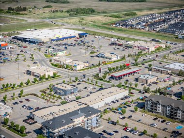 Birçok mağazası ve arabası olan bir alışveriş merkezinin şehir manzarası. Alışveriş merkezi boş ve otopark dolu.