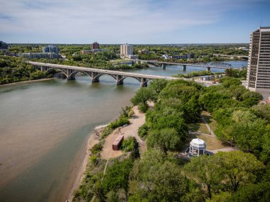 Köprü, arka planda bir şehir bulunan bir nehri kapsar. Köprü büyük bir yapıdır ve nehir sakindir.