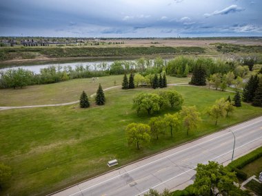 İçinden bir nehrin aktığı geniş, açık bir alan. Gökyüzü bulutlu ve çimenler yeşil