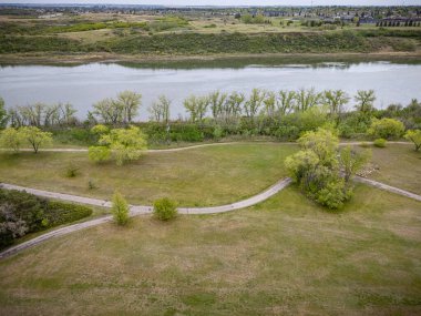 İçinden nehir akan otlak bir alan. Nehir sakin ve ağaçlar yeşil.