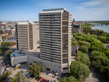 Önünde bir sürü pencere ve yeşil bir ağaç olan büyük bir bina. Bina çok sayıda park etmiş arabalar ve kamyonlarla çevrili.