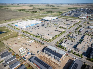 Ortasında bina olan büyük boş bir arazi. Her yer çitlerle çevrili. Park yerinde birkaç araba var.