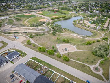 Göleti ve beyzbol sahası olan bir park. Park evlerle çevrili ve bir sürü yeşil çimeni var.