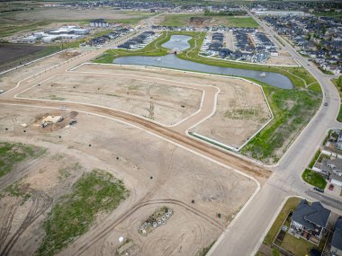 Ortasında büyük boş bir arazinin olduğu bir yerleşim alanı manzarası. Her yer evler ve göllerle çevrili.