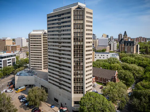 Yukarıdan birçok penceresi olan büyük bir bina görülüyor. Bina ağaçlar ve arabalarla çevrili.