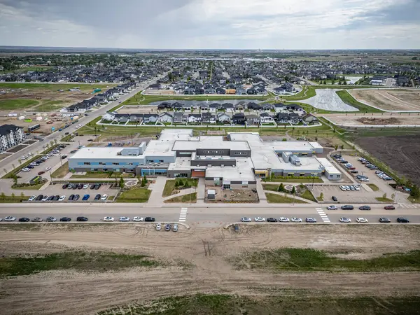 Önünde park yeri olan büyük bir bina. Otopark arabalarla dolu.