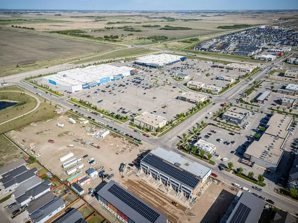 Ortasında bina olan büyük boş bir arazi. Her yer çitlerle çevrili. Park yerinde birkaç araba var.